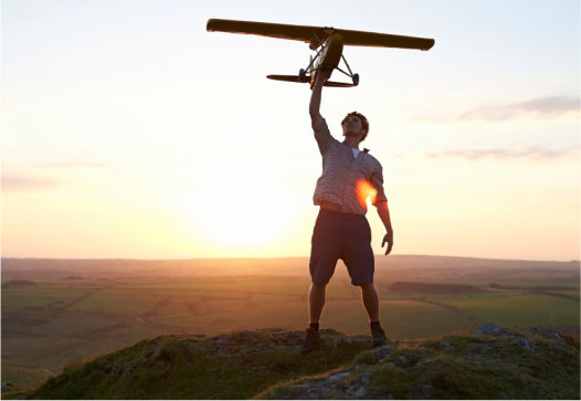 Person holding up airplane at sunset